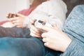 Cropped photo of two teenage boys children sitting on sofa at home, holding gamepad, playing videogames on game console. Royalty Free Stock Photo