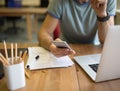 Closely hipster guy chatting in internet via cell telephone, sitting at desktop Royalty Free Stock Photo