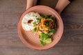 Cropped photo of woman holding pink plate with open flavorous burger with hole in bun, cut salmon, arugula, greenery.