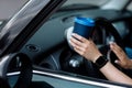 cropped photo of woman's hand holding blue paper cup of coffee in car. Hot drink take away. Travel with coffee Royalty Free Stock Photo