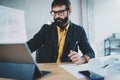 Cropped photo of young bearded male architect wearing eye glasses working on digital tablet dock at his desk Royalty Free Stock Photo