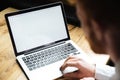 Cropped photo of young man using laptop on wooden table