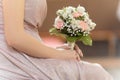 Cropped photo of young woman bride wearing long pink wedding dress, sitting holding bridal bouquet of white, pink roses. Royalty Free Stock Photo