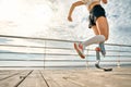 Cropped photo of a young woman with a prosthetic leg running on the bridge. Female sportsperson training outdoors