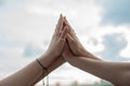 Cropped photo of young women folding hands, giving high five, clapping on sky background. Symbol of unity, friendship.