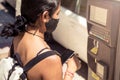 Cropped photograph of woman paying the parking ticket at the machine with the mobile. Girl wears a mask to avoid contagion on the Royalty Free Stock Photo