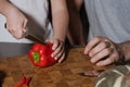 Cropped portrait of father and kid's hands cutting red bell pepper