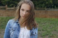 Cropped portrait of a girl in a denim jacket with developing hair. Caucasian teenage girl looking to the side outdoor, close up. Royalty Free Stock Photo
