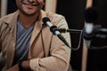 Cropped portrait of happy young male radio host smiling at camera while talking, broadcasting in studio using microphone Royalty Free Stock Photo