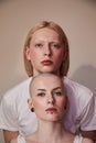 Womanly long haired man standing behind the bald masculine woman while posing