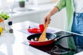 Cropped portrait of woman arm hold wooden spatula sausage eggs frying pan bright kitchen furniture inside Royalty Free Stock Photo