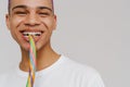 Cropped portrait of young handsome smiling boy biting rainbow candy