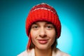 Cropped portrait of young merry girl in red winter hat smiling at camera isolated over blue background Royalty Free Stock Photo