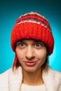 Cropped portrait of young merry girl in red winter hat smiling at camera isolated over blue background Royalty Free Stock Photo