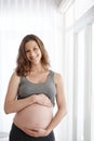 Embracing my maternal instincts. Cropped portrait of a young pregnant woman standing in her home.