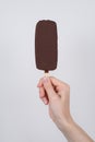 Cropped pov first person close up view photo of hand holding tasty delicious covered in dark chocolate icecream isolated grey Royalty Free Stock Photo