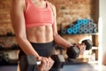 Cropped shot of athletic woman showing muscle while working out using dumbbells in gym. Sport, healthy lifestyle concept Royalty Free Stock Photo