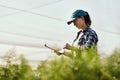 The greener the better. Cropped shot of an attractive young female farmer looking over paperwork while working on her