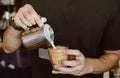 Cropped shot of Barista making cappuccino or latte by pouring milk in coffee cup for make latte art. Royalty Free Stock Photo