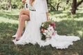 cropped shot of bride in wedding dress sitting on chair and holding bouquet of Royalty Free Stock Photo