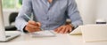 Businessman holding pen writing on empty notebook at office desk. Royalty Free Stock Photo