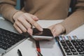 Cropped shot businesswoman hand using digital mobile phone calculating with document report on desk Royalty Free Stock Photo