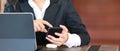 A businesswoman in suit sitting at her workspace working on tablet and using smart phone.