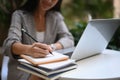 Businesswoman working on laptop computer and making notes in a notebook. Royalty Free Stock Photo