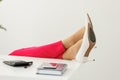 Cropped shot of businesswoman& x27;s legs in red pants and white high heels shoes on office desk relaxing during break at Royalty Free Stock Photo