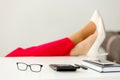 Cropped shot of businesswoman& x27;s legs in red pants and white high heels shoes on office desk relaxing during break at Royalty Free Stock Photo
