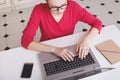 Cropped shot of busy female freelancer works remotely at home, keyboards something on portable laptop computer, surrounded with sm Royalty Free Stock Photo