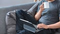 Casual man drinking coffee and using computer tablet on couch. Royalty Free Stock Photo