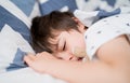 Cropped shot Child boy sleep with his eyes half open on his bed, Close up Young Kid sleeping with open eyed while taking a nap, Royalty Free Stock Photo