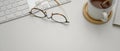 Copy space on white worktable with glasses, computer keyboard and hot cocoa cup Royalty Free Stock Photo