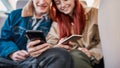 Cropped shot of a couple of teenagers smiling, using their smartphones while sitting on back seat in the car Royalty Free Stock Photo