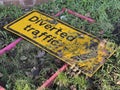 Yellow diverted traffic sign thrown away in the grass