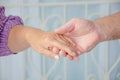 Cropped shot of elderly couple holding hands while sitting together at home, Concept of take care together, Focus on hands Royalty Free Stock Photo