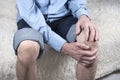 Cropped shot of elderly man sitting on sofa and suffering from pain in knee. Joint disease, arthritis, arthrosis Royalty Free Stock Photo