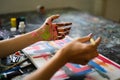 Cropped shot of female artist with dirty hands painting with paintbrush and watercolors on canvas Royalty Free Stock Photo