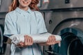 cropped shot of female dry cleaning worker holding stack of clean