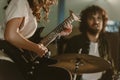 cropped shot of female guitarist performing song with blurred drummer