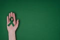 cropped shot of female hand with green awareness ribbon for Green awareness ribbon for Scoliosis, mental health symbol