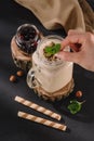 cropped shot of female hand putting mint in milkshake, sweet straws, walnuts