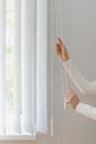 Woman open white fabric vertical jalousie in room Royalty Free Stock Photo