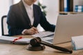 cropped shot of female lawyer doing paperwork at workplace with laptop and gavel