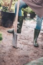Gardener in rubber boots with spade in garden