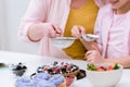 cropped shot of grandmother and little granddaughter pouring sugar powder onto tart