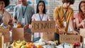 Cropped shot of group of diverse young volunteers packing food and drinks donation, Woman holding card with Donate Royalty Free Stock Photo