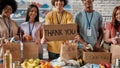 Cropped shot of group of diverse young volunteers packing food and drinks donation, Guy holding card with Thank you Royalty Free Stock Photo