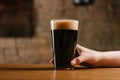cropped shot of hand holding glass of fresh dark beer in pub Royalty Free Stock Photo